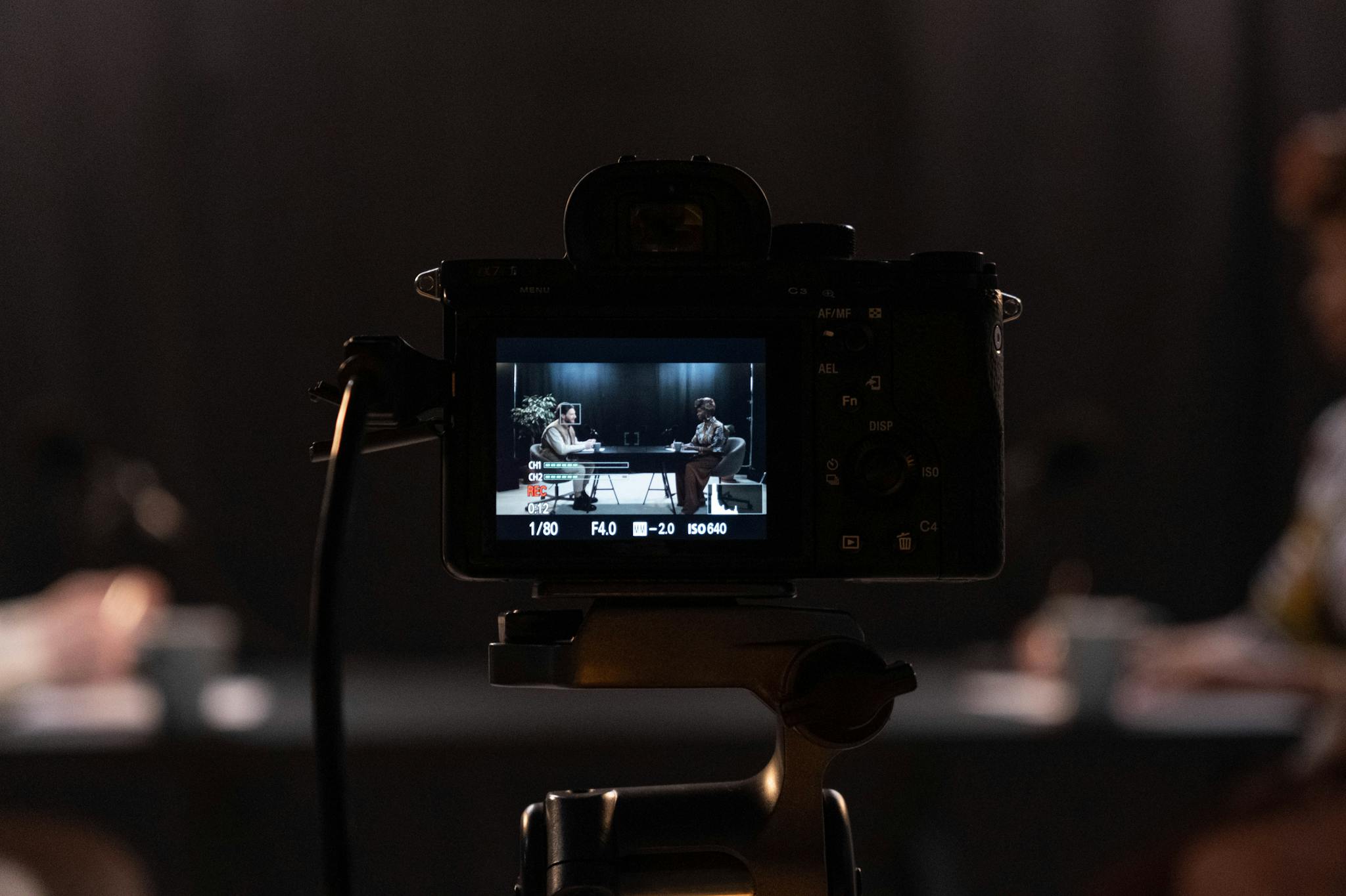Close-up of a camera recording a podcast interview in a studio setting.