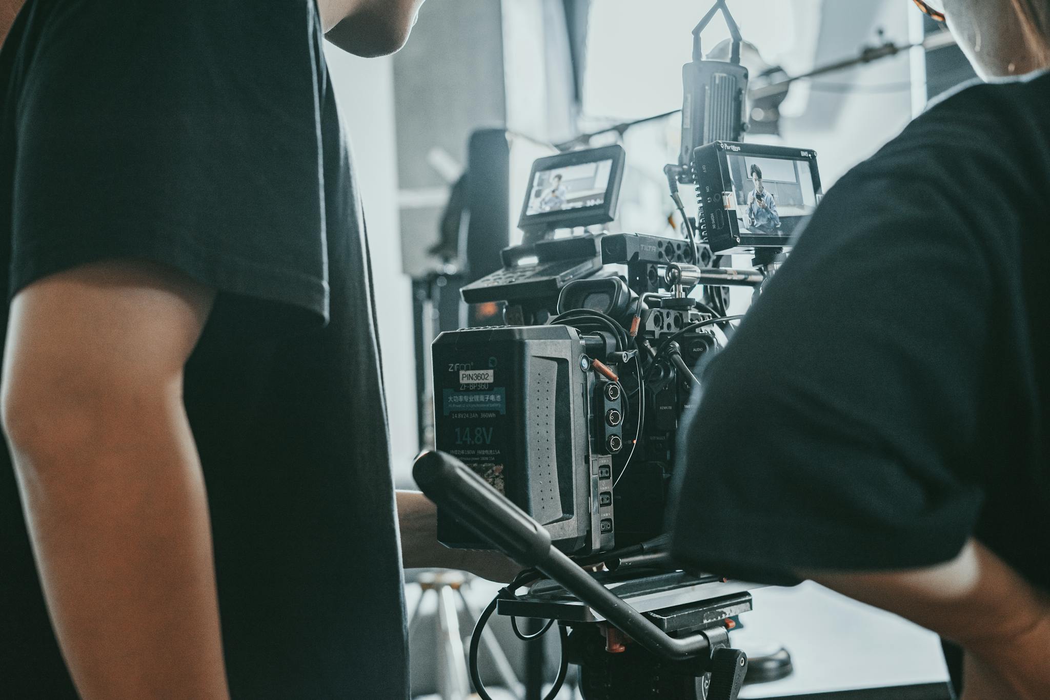 Close-up of a film crew operating professional camera equipment indoors.